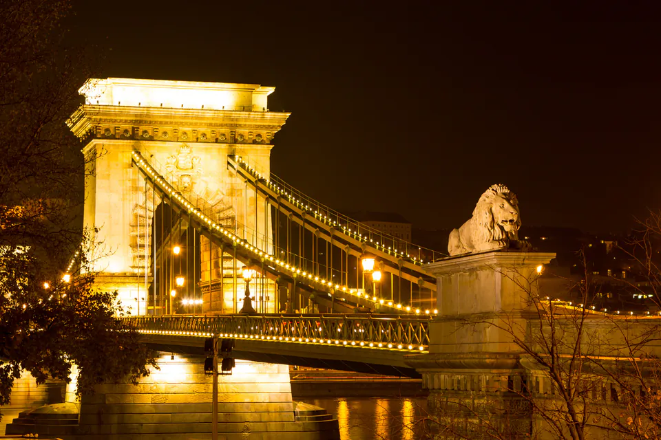 Chain Bridge illuminated at night with golden lights reflecting on Danube River