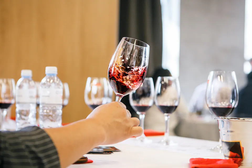 Wine glass being swirled at a wine tasting event with other glasses and water bottles on table