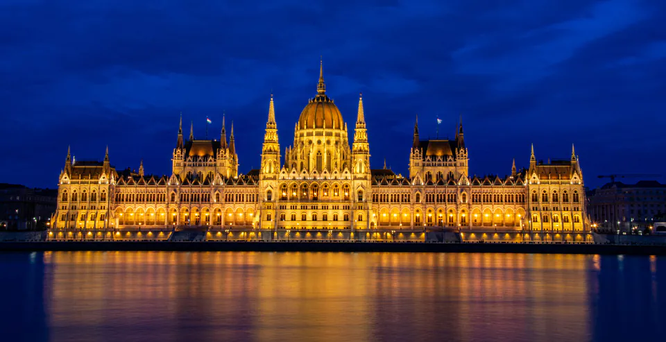 Hungarian Parliament building illuminated at night with golden lights reflecting on the Danube River