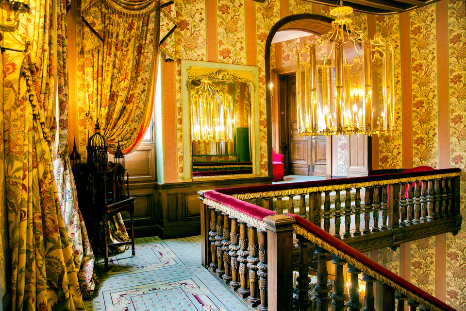 Ornate boutique hotel interior with golden wallpaper, vintage mirrors and chandelier lighting