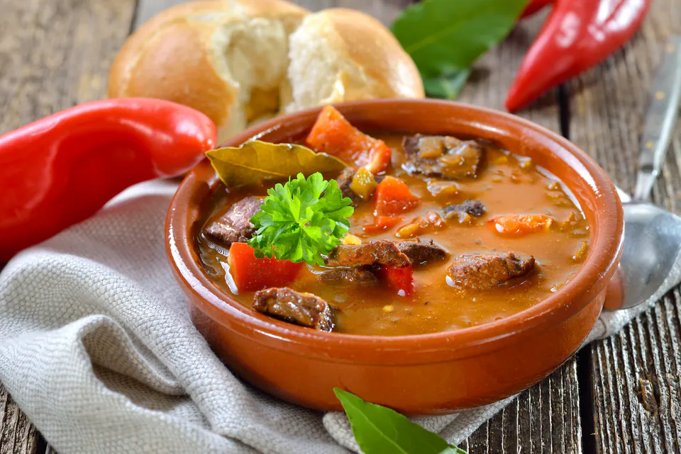 Traditional Hungarian goulash served in ceramic bowl with fresh bread and wine