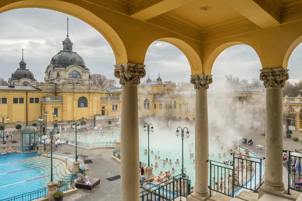 Steaming thermal pool viewed through classical arches at historic Budapest spa