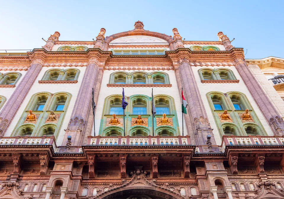 Ornate pink and turquoise Art Nouveau building facade with decorative columns and arched windows