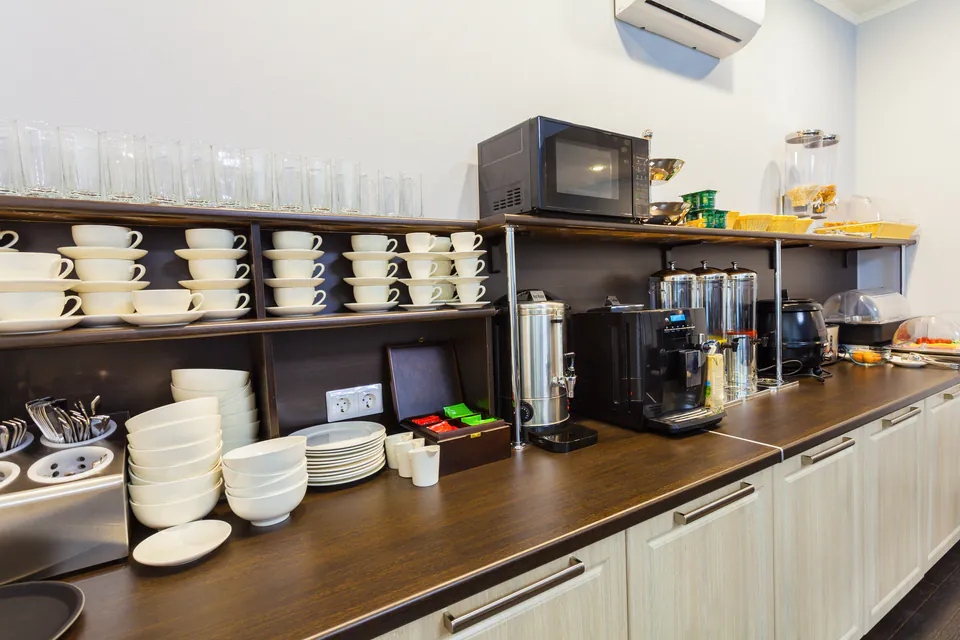 Shared kitchen counter with coffee makers, dishes, and microwave in hostel common area