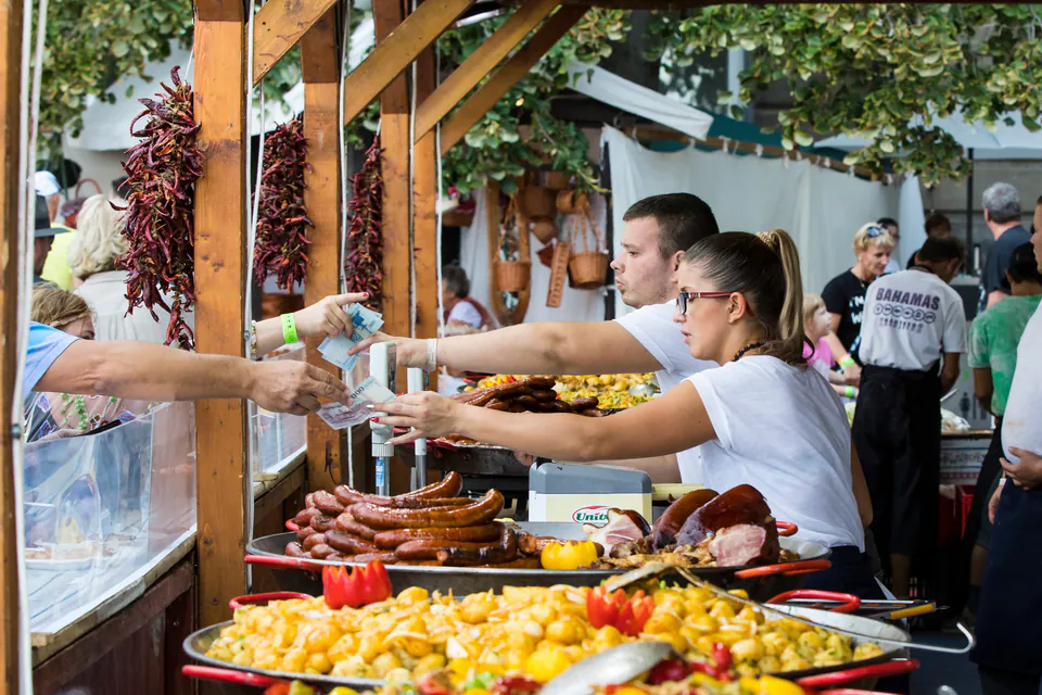 Food vendors serving traditional Hungarian dishes at an outdoor festival stall