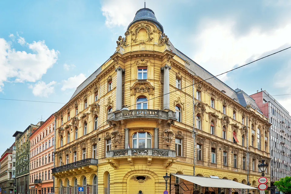 Renovated yellow corner building with ornate architectural details and balconies in District 8