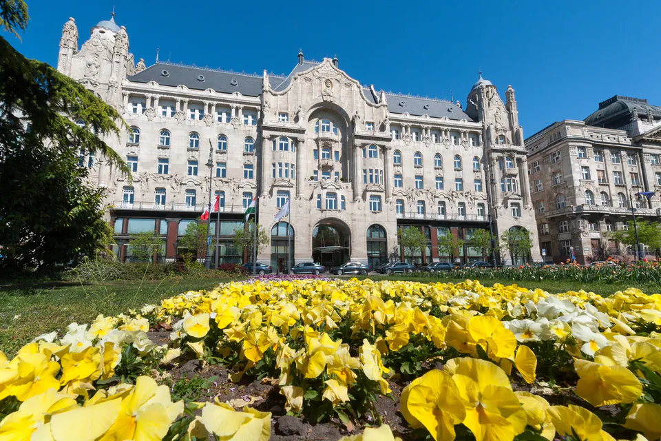 Historic Gresham Palace facade with ornate Art Nouveau architecture and yellow flowers in foreground