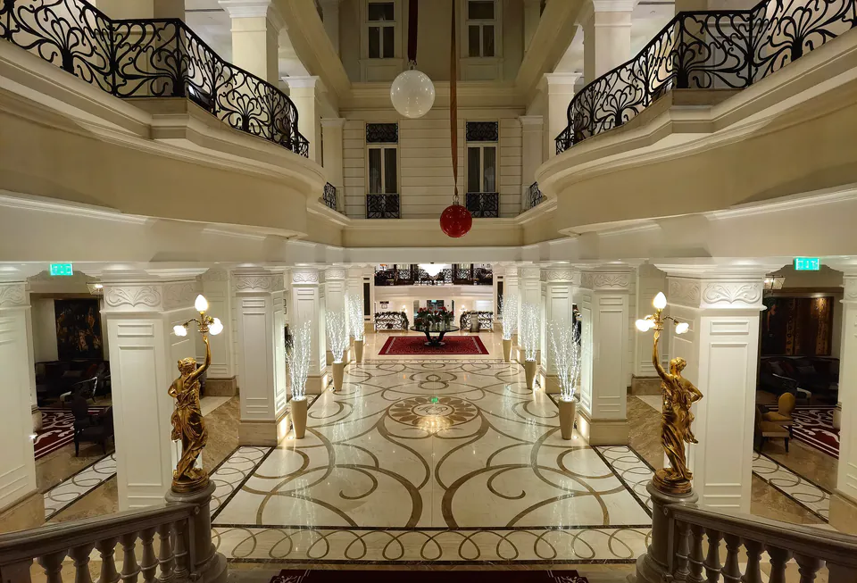 Elegant hotel interior with marble floors, ornate railings, and classical columns in white and gold