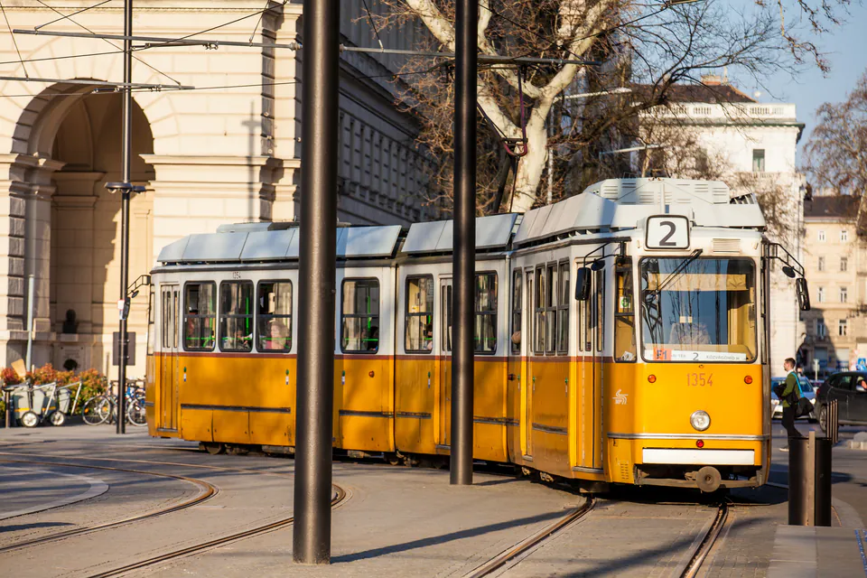 Historic yellow tram number 2 on tracks beside classical building in Budapest