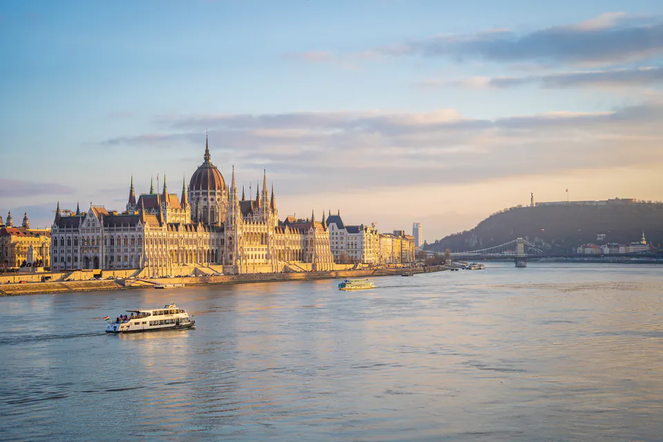 Sunset view of Hungarian Parliament Building with cruise boat on Danube River