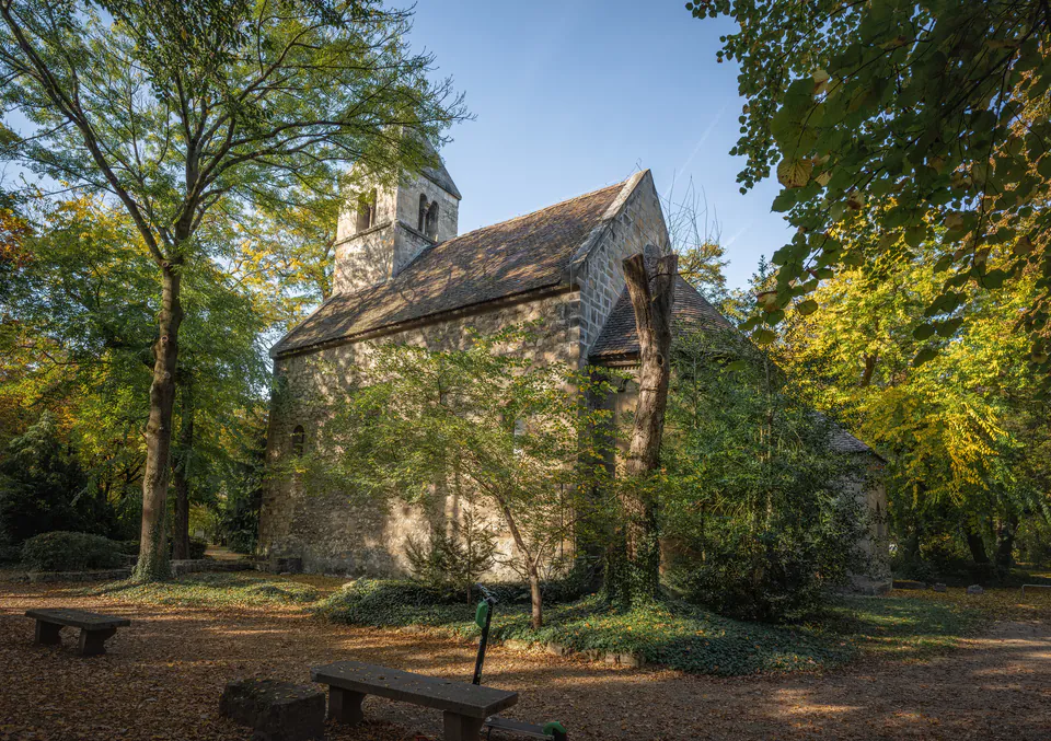 Ancient stone St. Michael Chapel surrounded by trees in morning light