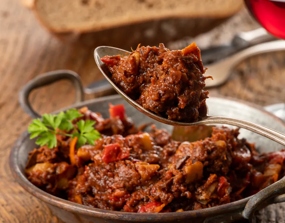 Rich Hungarian goulash stew served in traditional metal pot with vegetables and tender meat