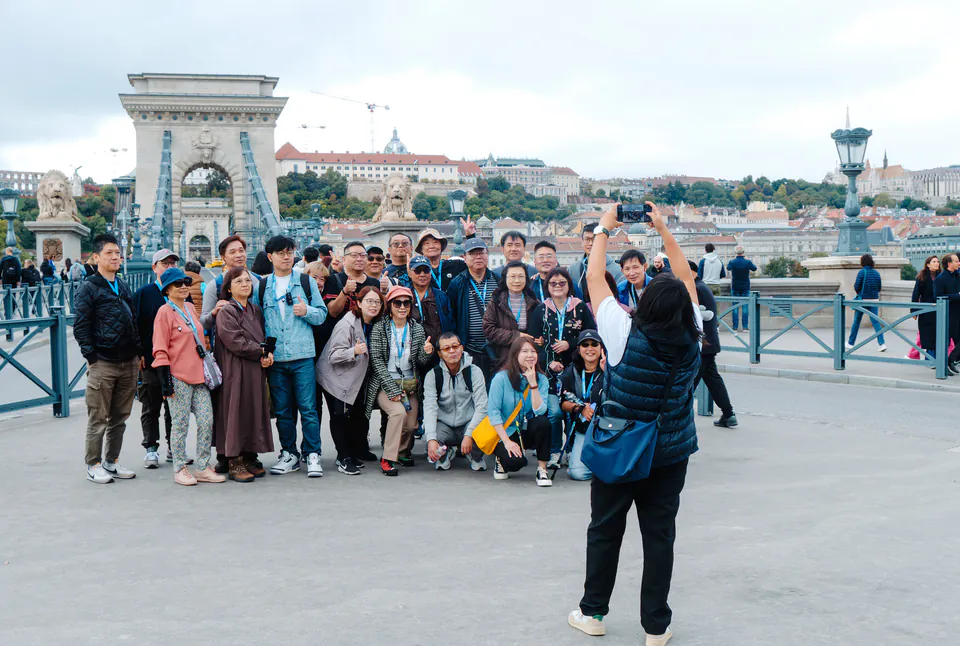 Tour group gathered on Chain Bridge with Buda Castle in background during evening light
