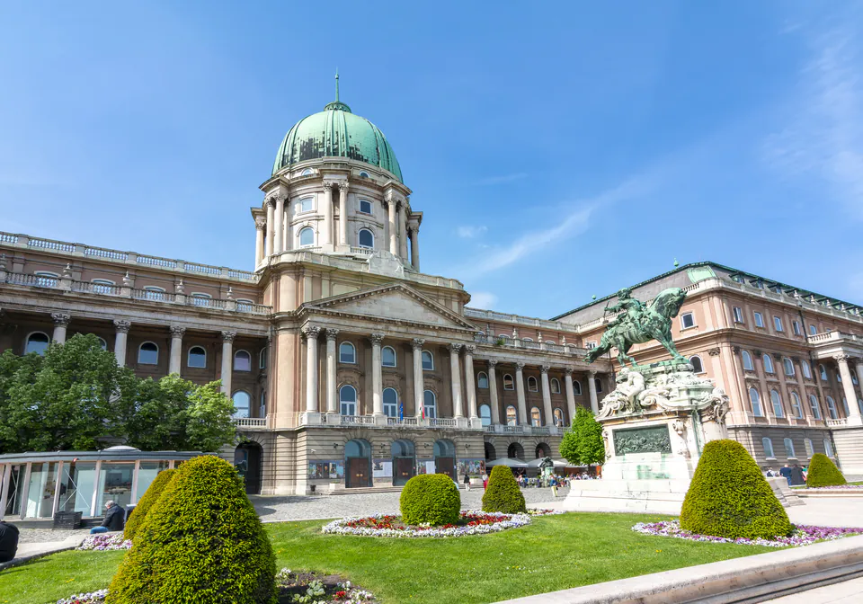 Couples walking through cobblestone courtyard of Buda Castle at twilight