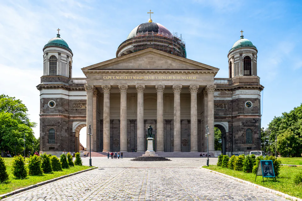 Neoclassical facade of Esztergom Basilica with grand columns and twin towers under blue sky