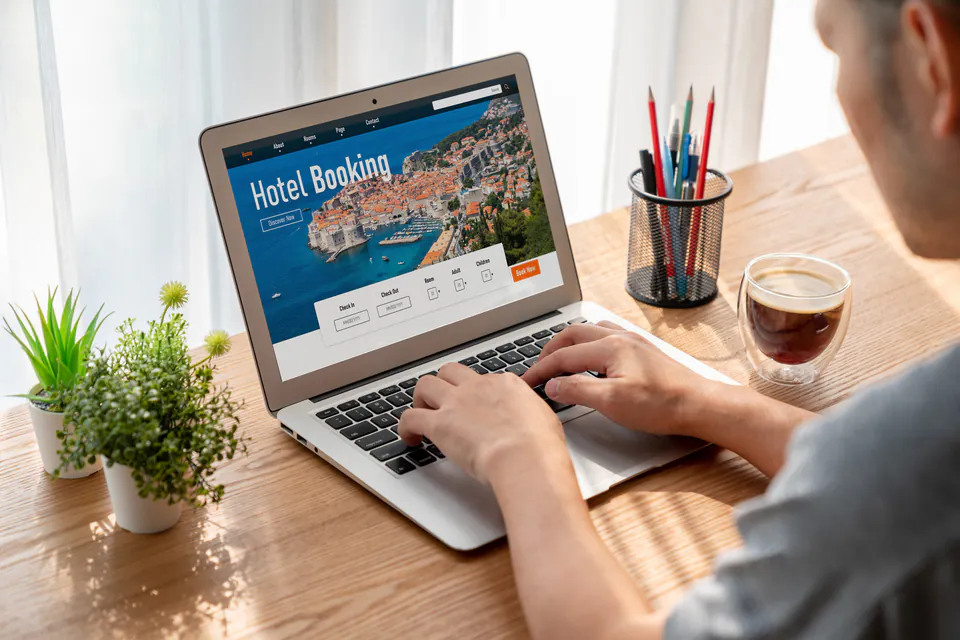 Person using laptop to book hotel online, showing 'Hotel Booking' page