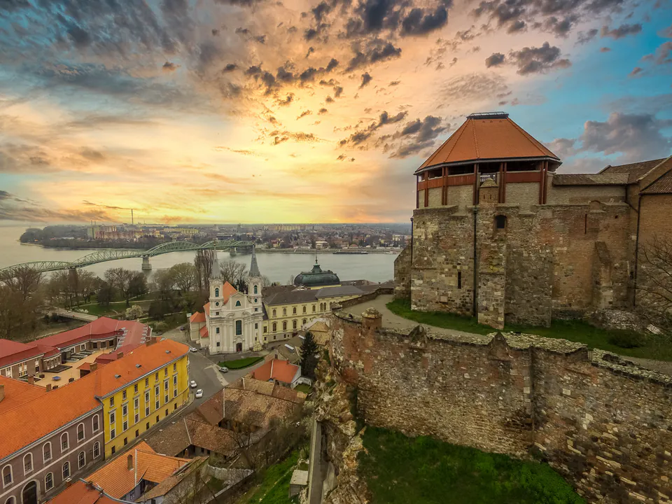 View from Esztergom Castle showing medieval walls, church and Mária Valéria Bridge at sunset