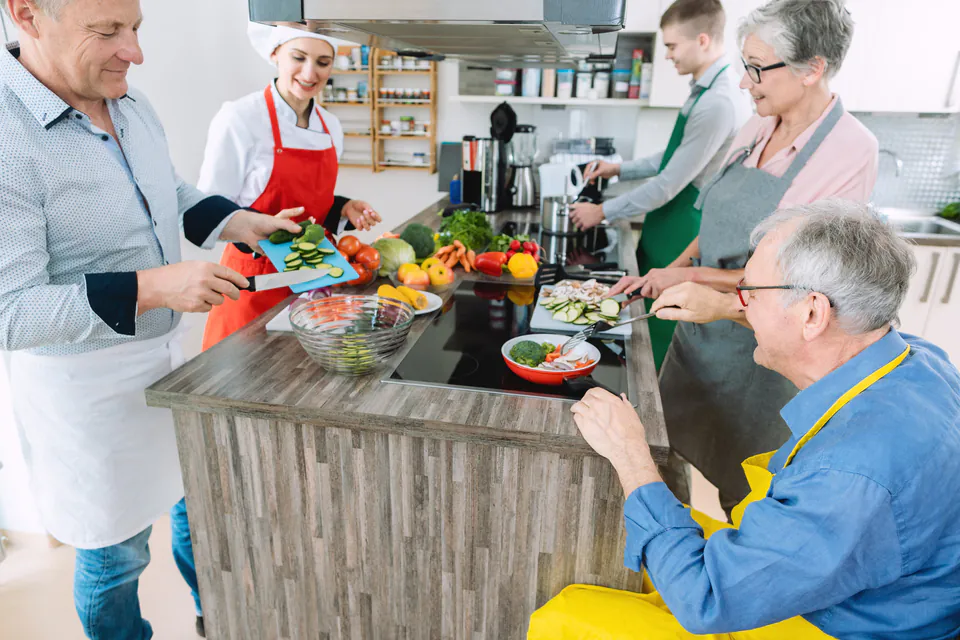 Cooking class participants preparing ingredients at a kitchen counter with instructors