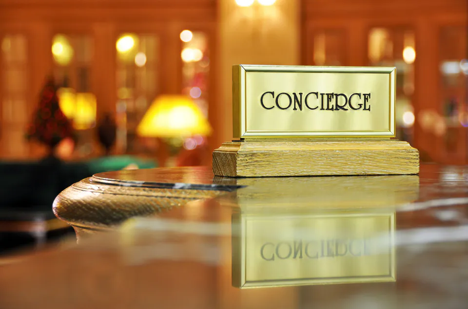 Elegant brass concierge desk sign on polished wooden counter in luxury hotel lobby