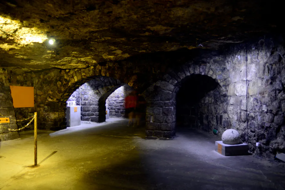 Medieval stone archways and corridors illuminated by atmospheric lighting in underground tunnel system
