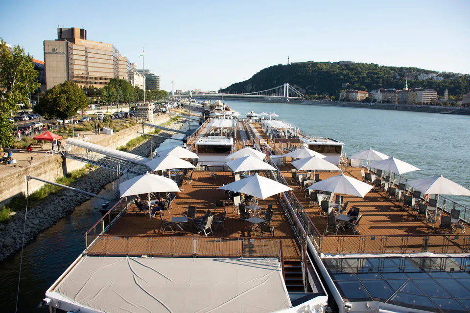 Riverside dining terrace with white umbrellas overlooking the Danube and Elizabeth Bridge in Budapest