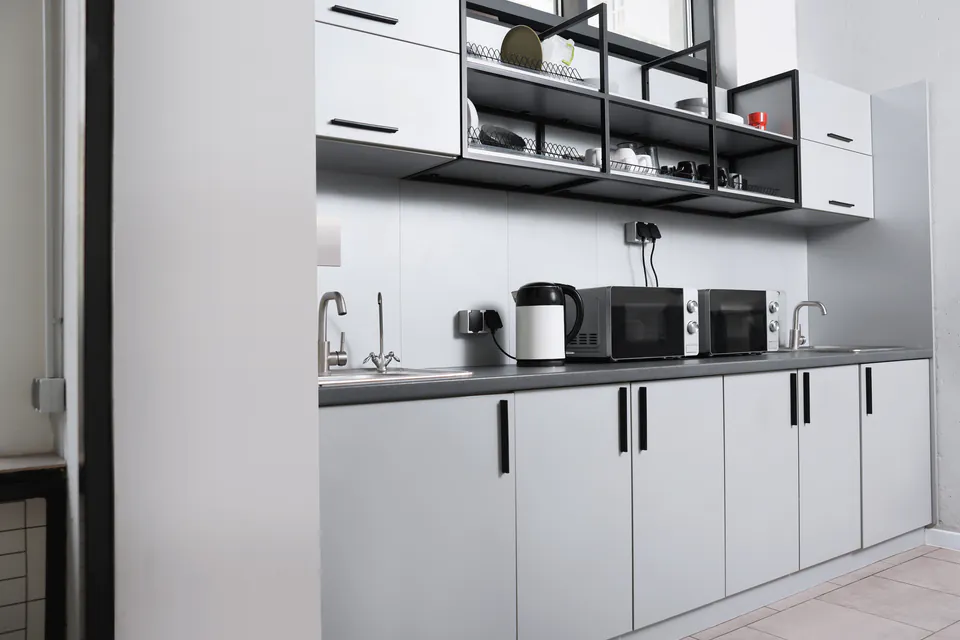 Modern white kitchen with microwave, kettle and cabinets in minimalist design