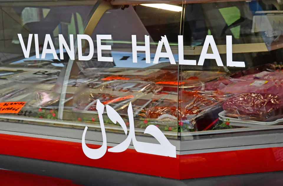 Halal butcher shop display with 'Viande Halal' and Arabic script on glass.