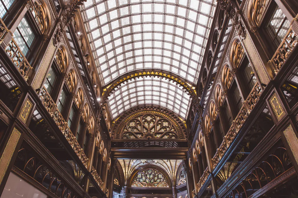 Historic glass-roofed arcade with ornate Art Nouveau architectural details and gilded decorations