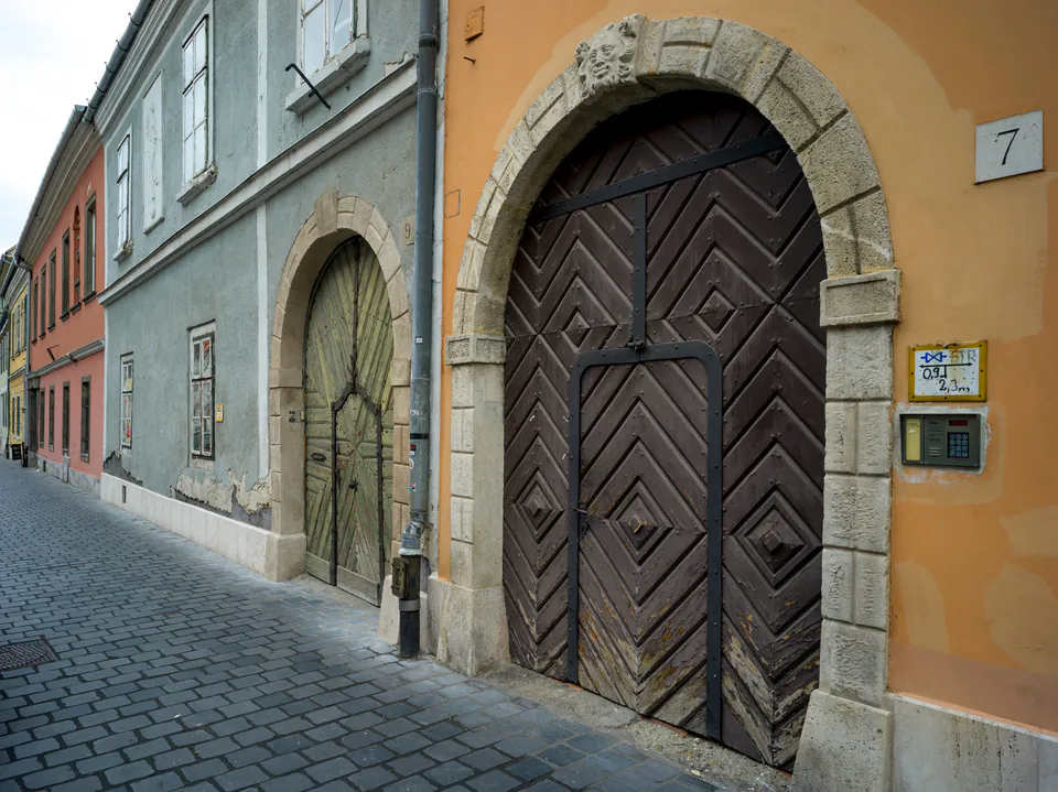 Historic doorways with arched entrances and cobblestone street in Budapest's Castle District