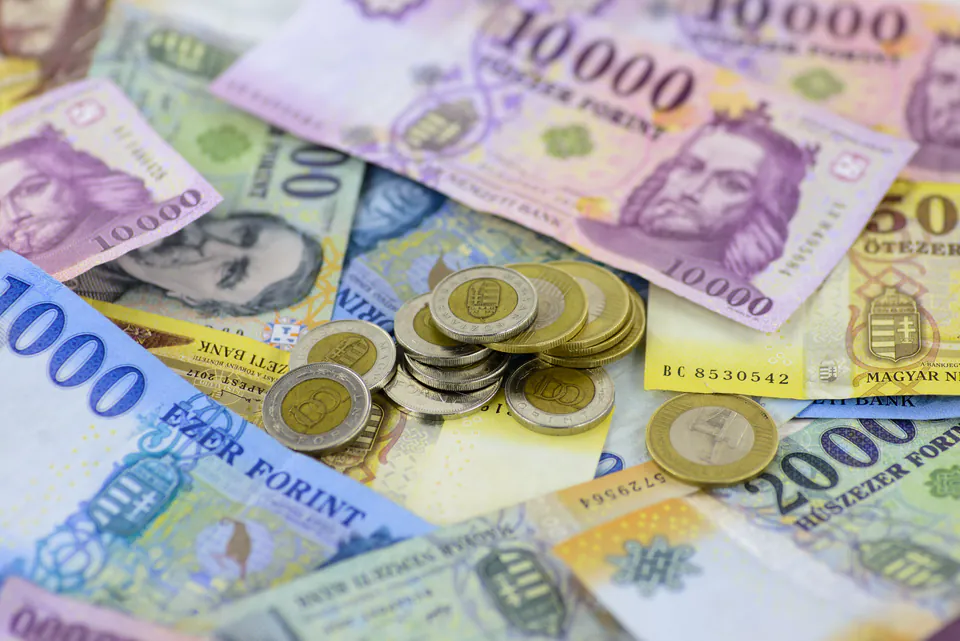 Hungarian forint banknotes and coins spread on wooden surface with calculator