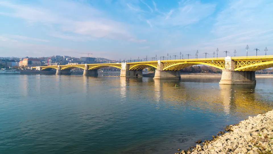 Margaret Bridge spans across Danube River with yellow arches and pedestrian walkways