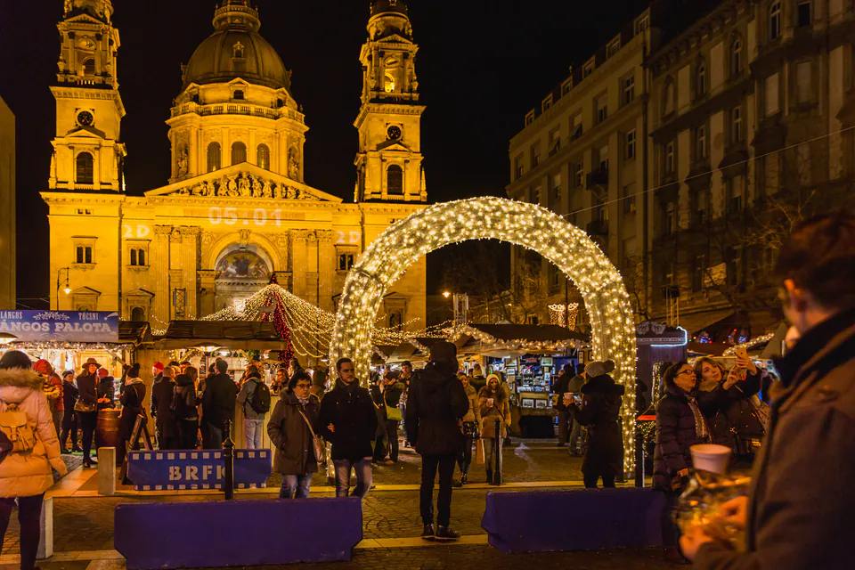 Illuminated St. Stephen's Basilica with Christmas market stalls and glowing archway at night