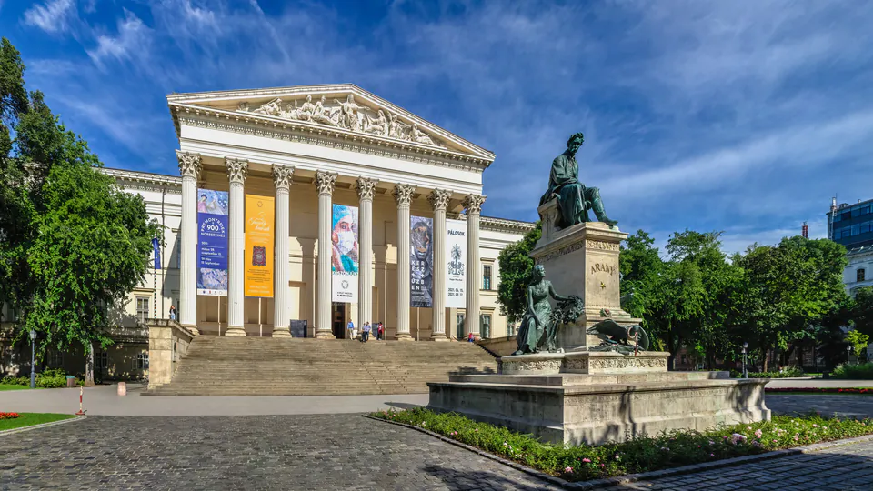 Neoclassical facade of Hungarian National Museum with columns and statue in foreground