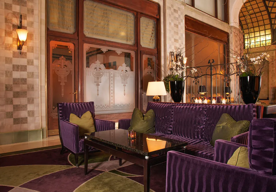 Elegant hotel lobby with purple velvet seating and decorative etched glass windows