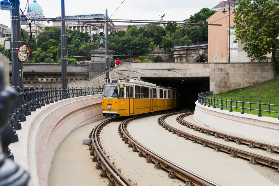 Yellow tram entering a tunnel on curved tracks in Budapest's public transit system
