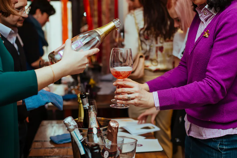 Wine pouring and tasting at a festival event with people holding glasses
