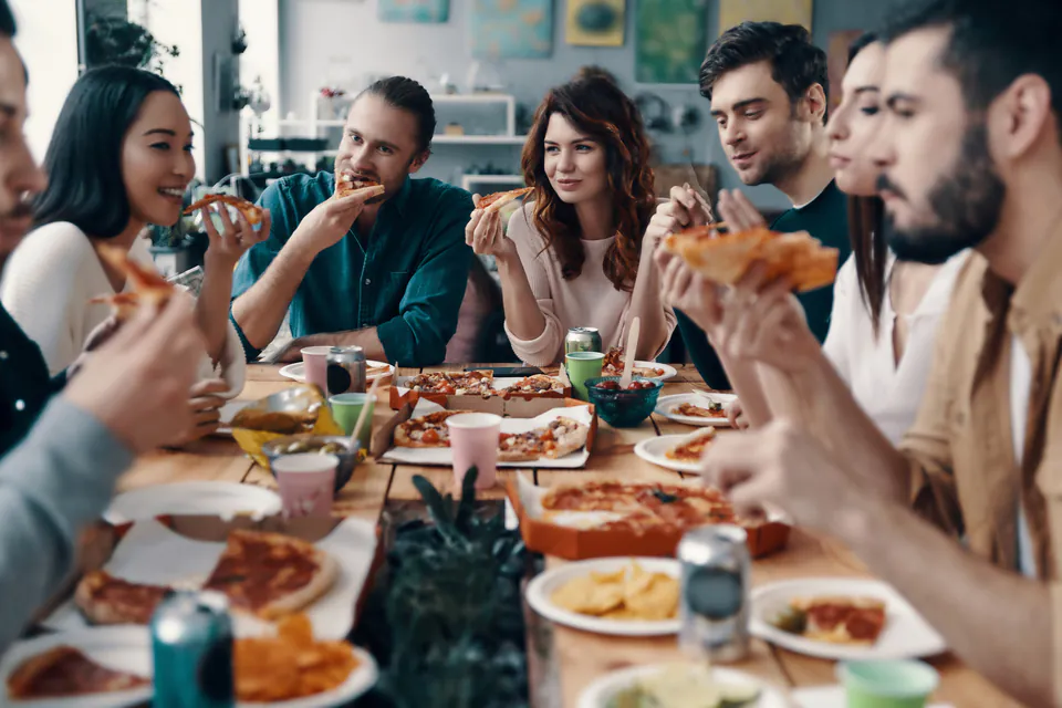 Group of people enjoying a meal together at a dining table with shared dishes