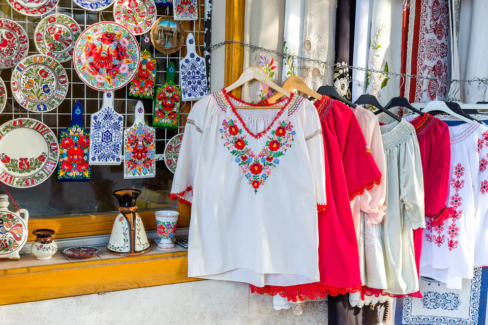 Traditional Hungarian embroidered clothing and decorated plates displayed at market stall