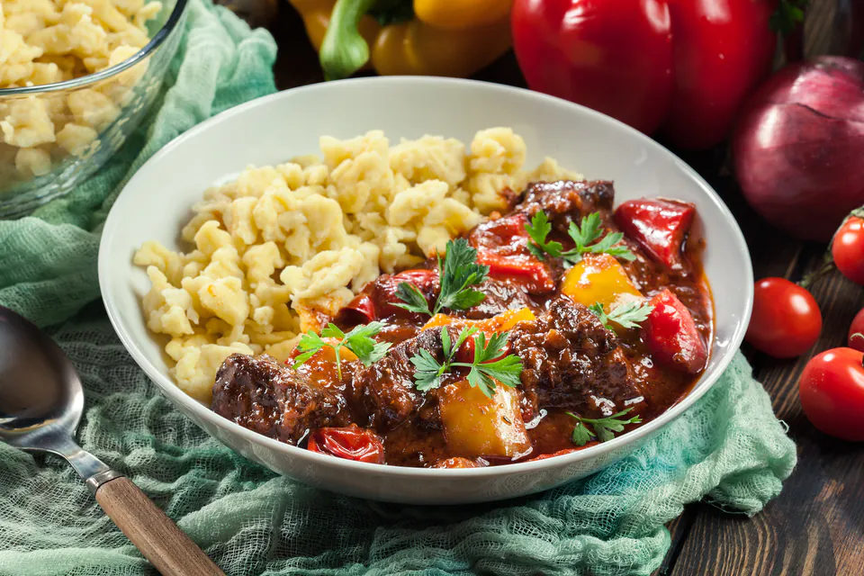 Traditional Hungarian goulash served with spaetzle noodles, garnished with fresh parsley