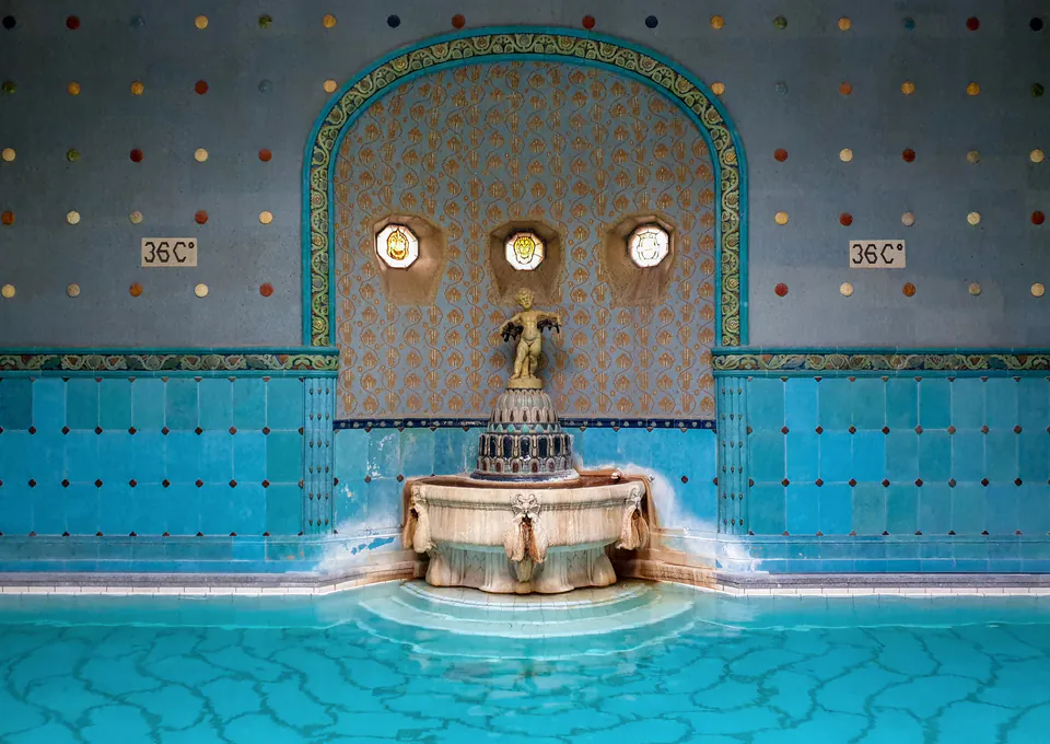Ornate Art Nouveau thermal pool with turquoise tiles and decorative fountain at Gellért Baths