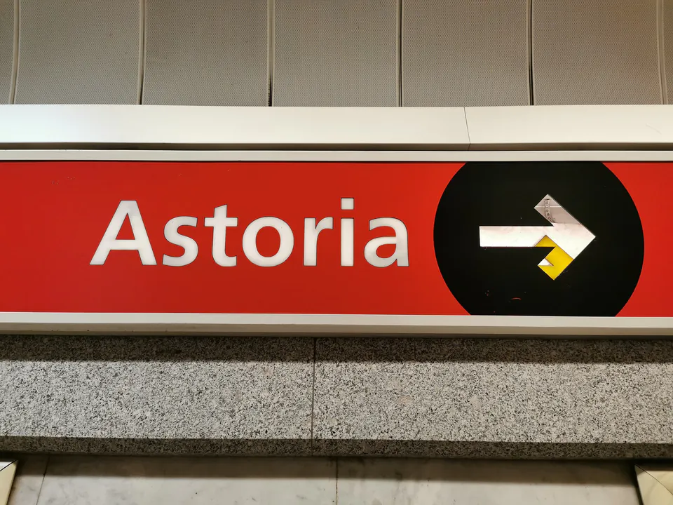 Astoria station signage with directional arrow on red background