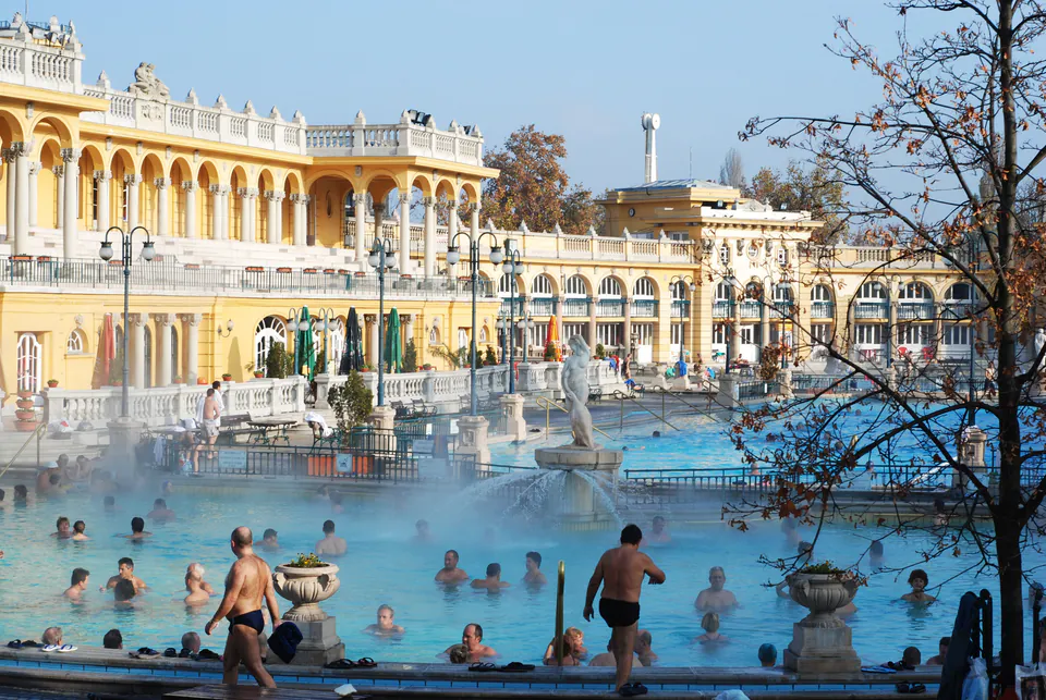 Steaming outdoor thermal pool at Széchenyi Baths with yellow Neo-baroque architecture in background