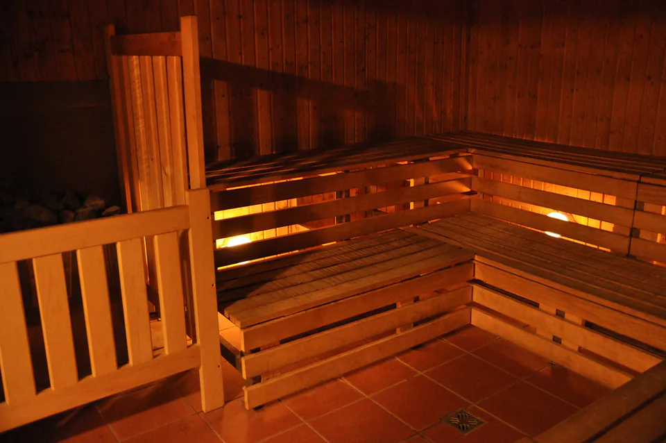 Traditional wooden sauna interior with tiered benches illuminated by warm lighting