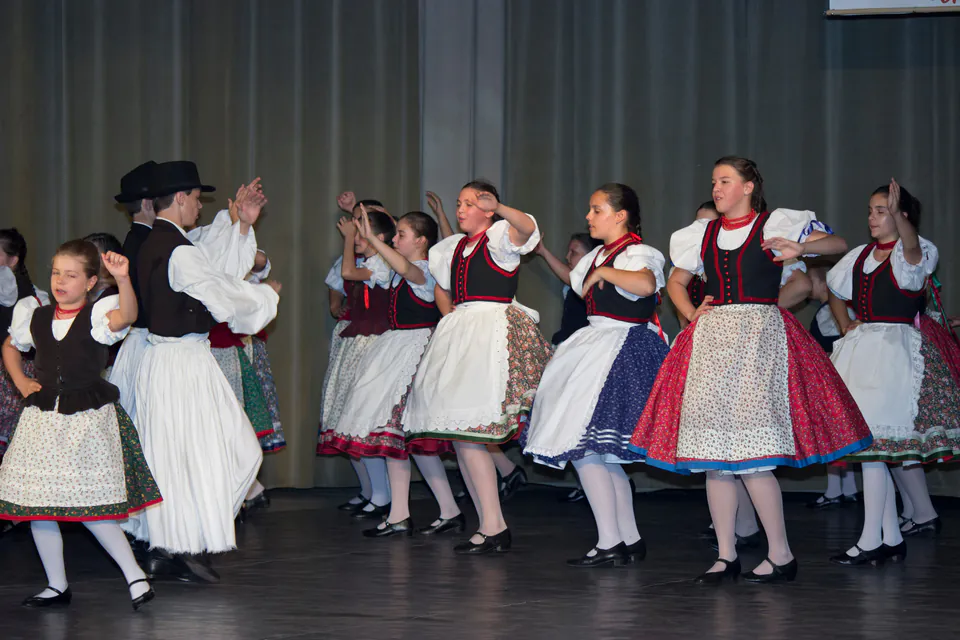 Folk dancers in traditional Hungarian costumes performing choreographed movements on stage