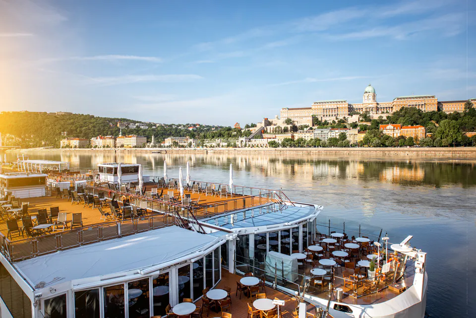 Multi-level floating restaurant deck with dining tables overlooking Buda Castle and Danube River