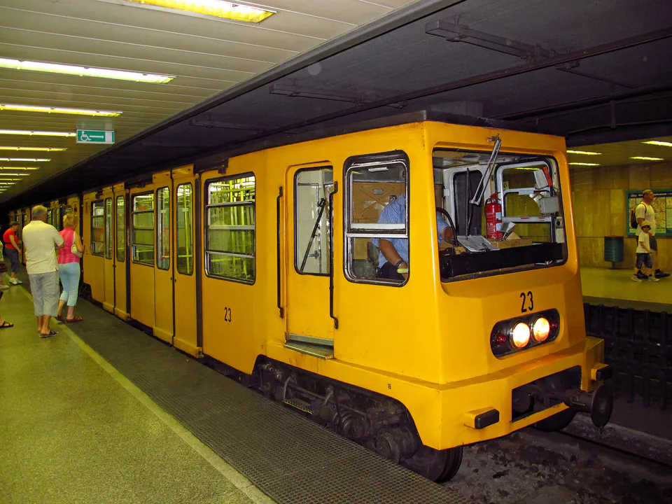 Budapest metro station platform with arriving yellow train