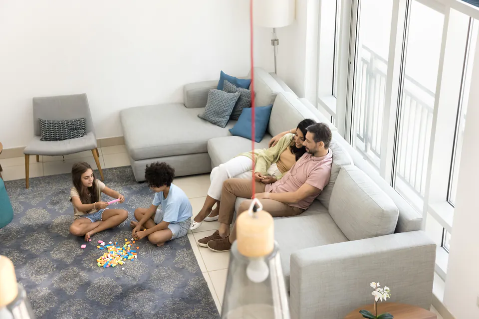 Modern apartment living room with sectional sofa and children playing on floor