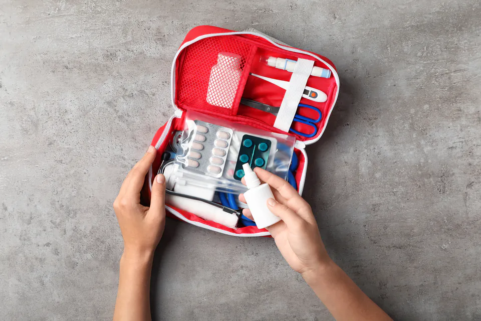 Person packing medical essentials for travel including medications and insurance documents