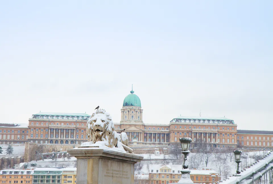 Snow-covered medieval streets in Buda Castle District during winter evening with warm lamplight