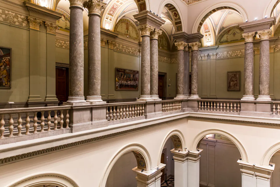 Ornate classical interior gallery with marble columns and arched walkways in a Budapest museum